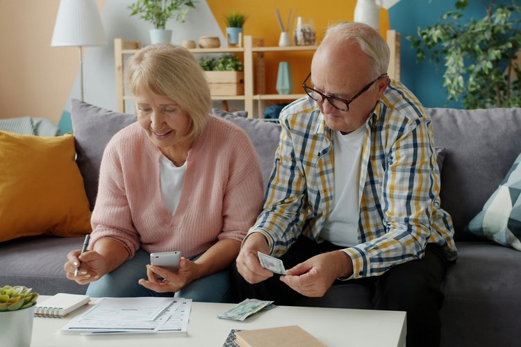 Älteres Paar überprüft Finanzen zu Hause auf der Couch.